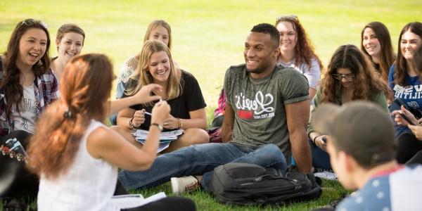 Students sitting together in the grass on campus.